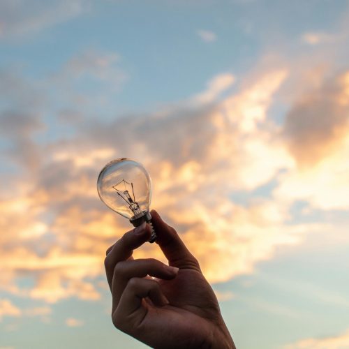 pexels-photo-1314410-1314410 A hand holds a light bulb against a scenic sunset sky, symbolizing creativity and innovation.